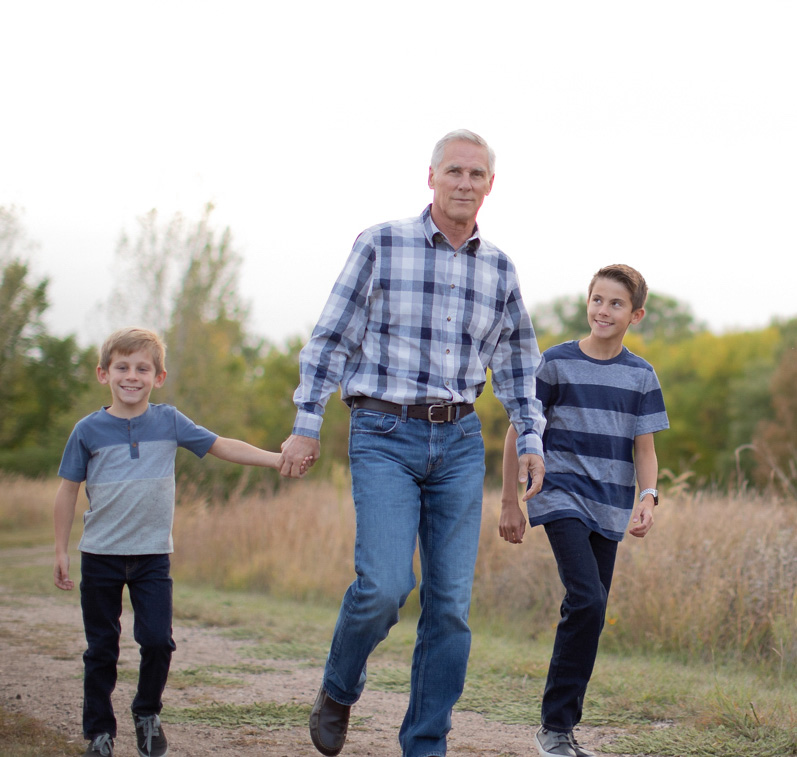 Happy grandfather walking in a field with grandsons 